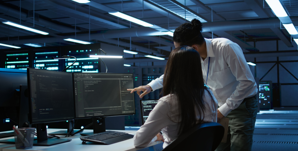 Profissionais de TI monitorando sistemas em computadores em um centro de dados, representando proteção de dados nas empresas e práticas de segurança da informação