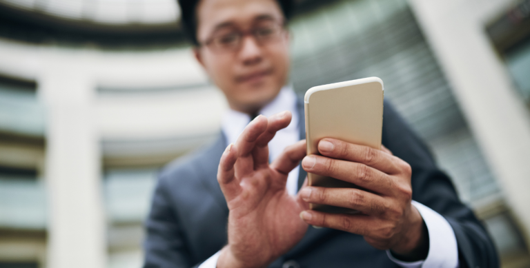 Profissional em ambiente externo utilizando celular corporativo, com destaque para bloquear celular roubado em caso de perda ou furto e exposição de dados sensíveis fora do ambiente seguro.